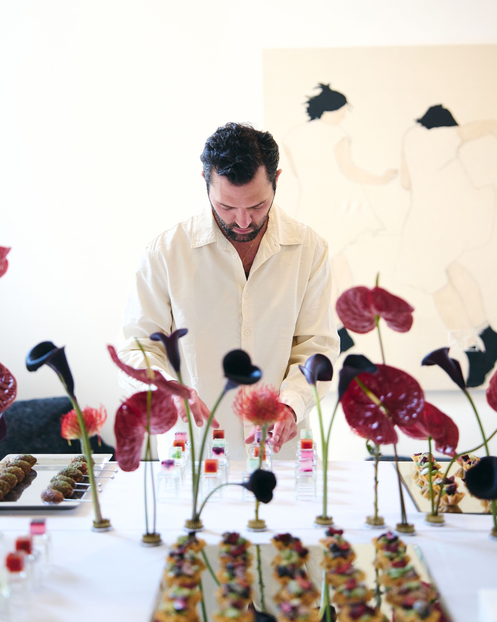 Jérémy prépare une table de réception parmi des compositions florales